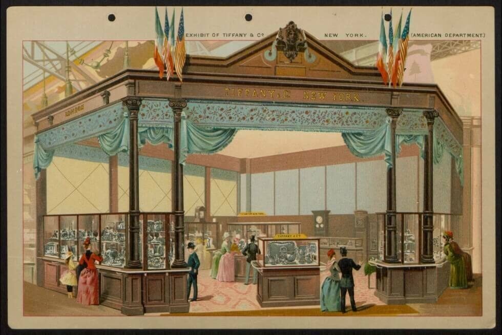 A vintage exhibition booth with ornate decorations, people browsing displays and jewellery