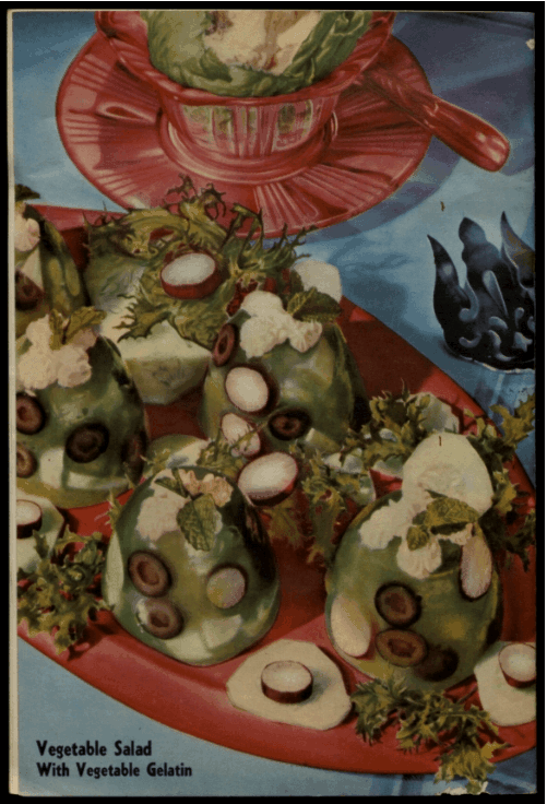 Colourful vegetable salad shaped in moulds, garnished with olives and greens on a red platter
