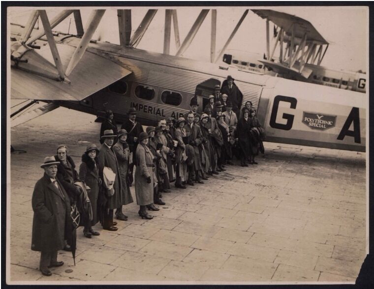 A large group of people standing beside a vintage airplane with the letters G A visible