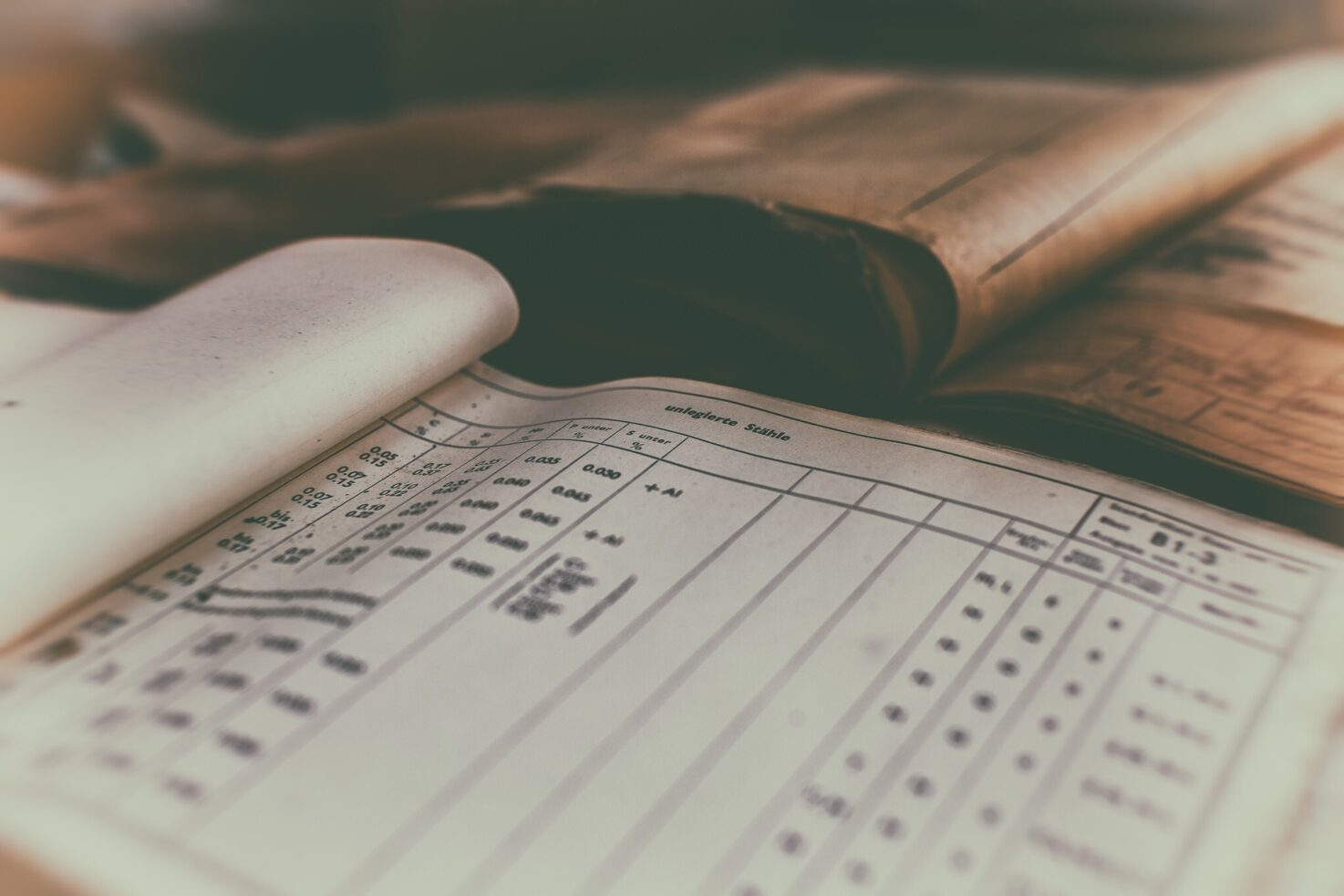 Open ledger sheet with printed data and an old book in the background.
