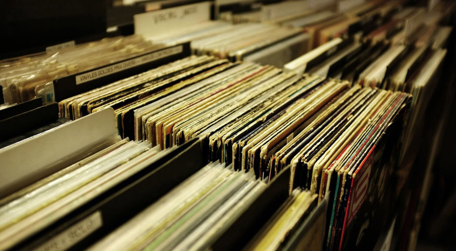 Many rows of vinyl records stored in a cardboard box, some are partially visible.