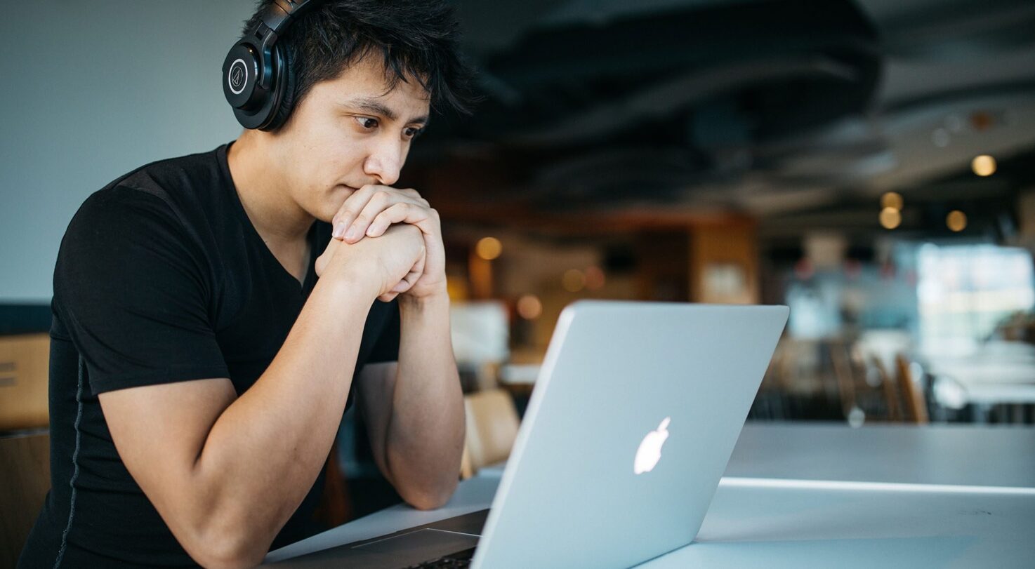 A person wearing headphones looking at a laptop.