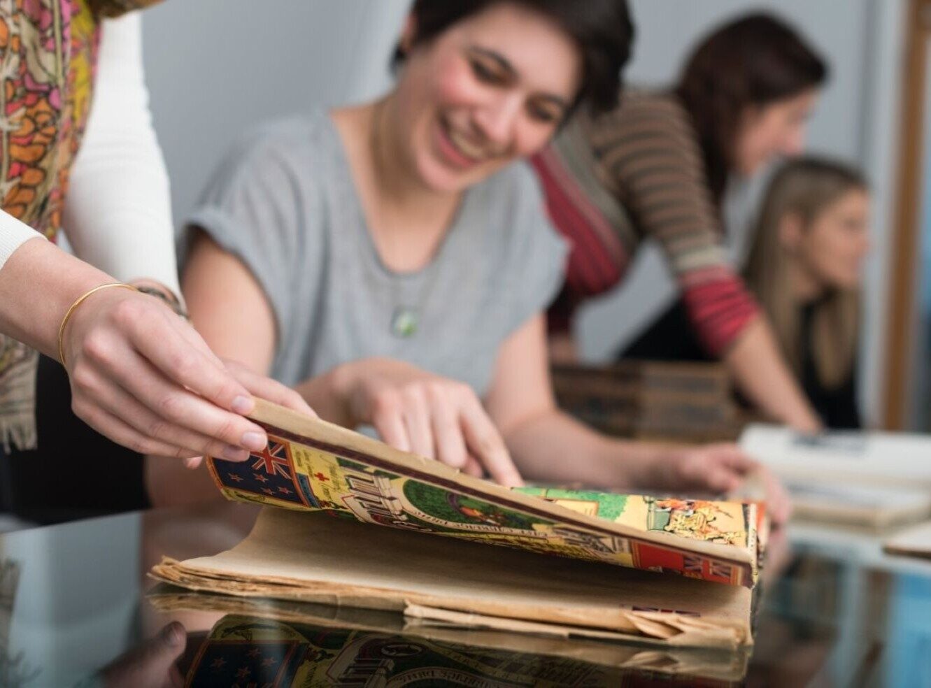 People browsing and discussing colourful, old-fashioned illustrated books.