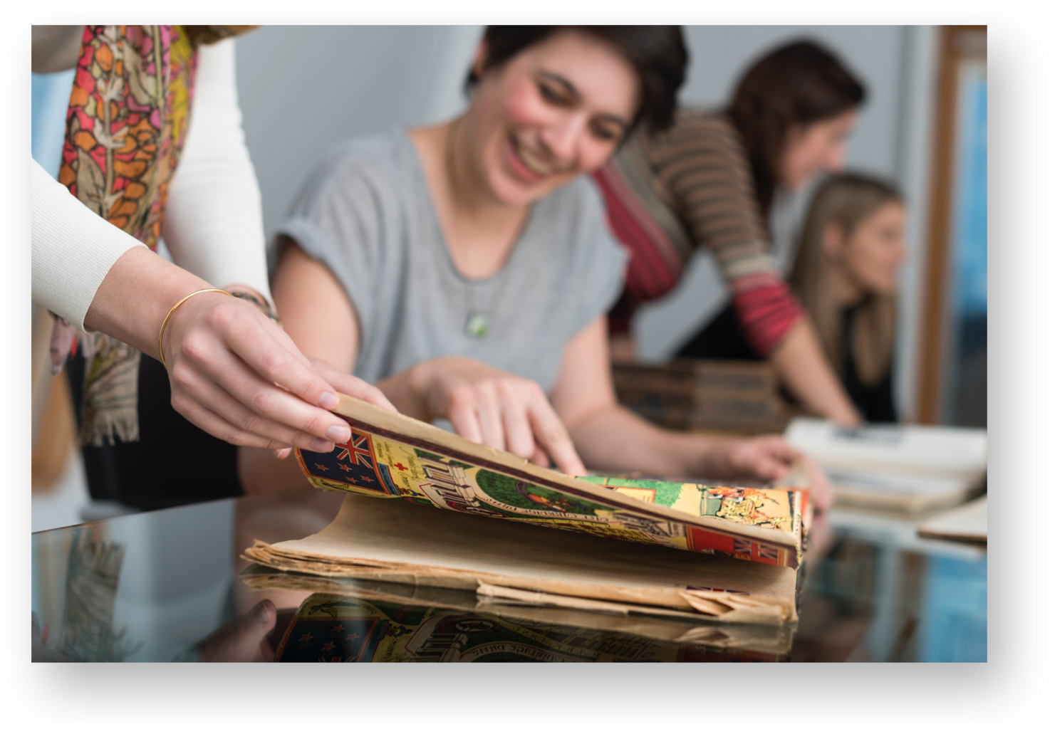People browsing and discussing colourful, old-fashioned illustrated books.