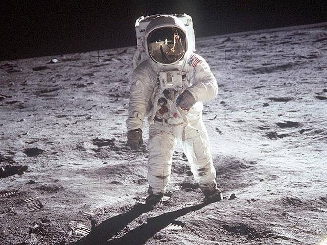An astronaut in a spacesuit walking on the moon's surface, with footprints visible.