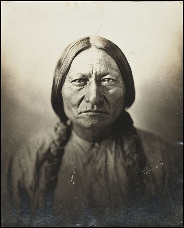An Indigenous North American person with long hair, wearing a light-coloured shirt, facing the camera head-on.