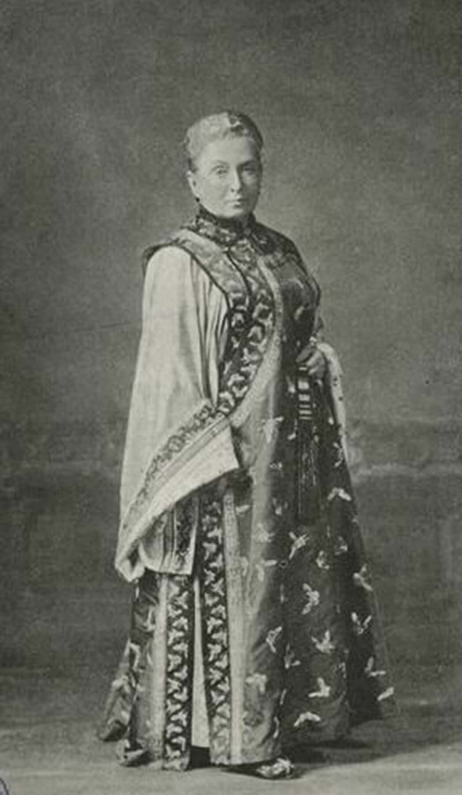 A woman wearing a decorative long dress with intricate patterns and a shawl