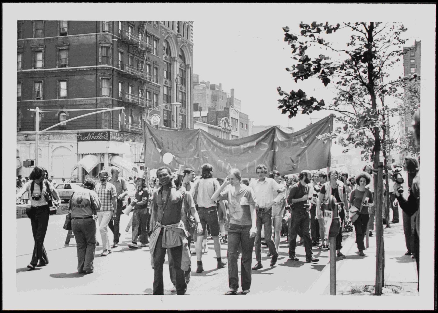 A crowd of people holding a large banner during a protest on a city street