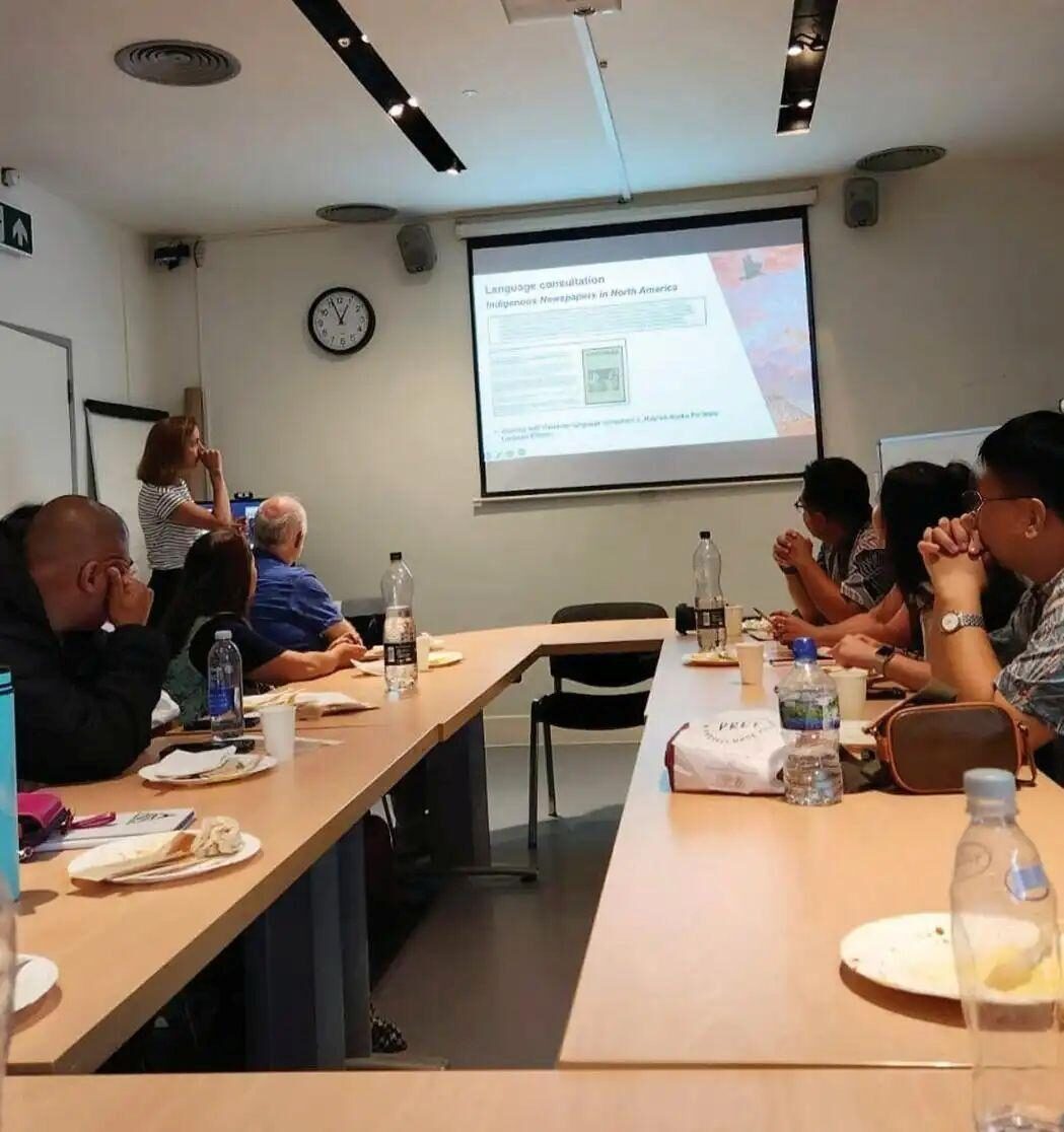 A group of people in a meeting room listening to a presentation on Indigenous newspapers.