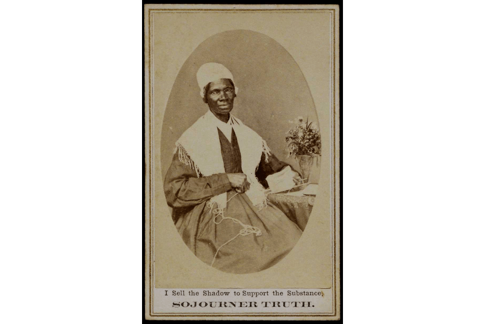 A historical figure, Sojourner Truth, seated with a decorative flower in a vase on her lap, dressed in a traditional outfit