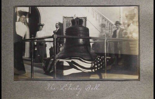 The Liberty Bell displayed in a glass enclosure with visitors admiring it.
