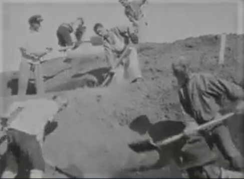 A group of workers digging earth with shovels on a construction site.