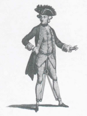 An actress dressed as a man in eighteenth-century attire, wearing a large hat, standing with hands on hips.