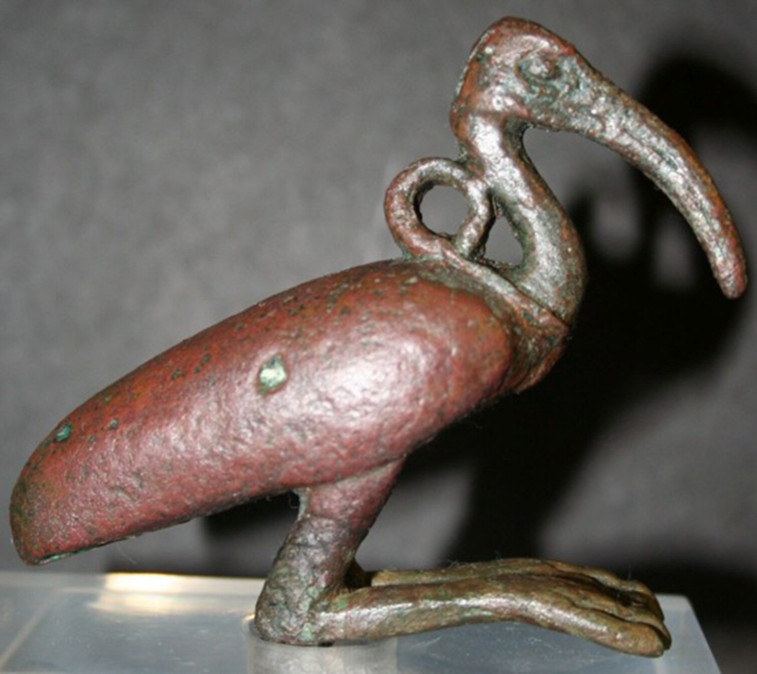 A bronze bird statue with a long beak and rounded body, showing weathered green and brown tones.