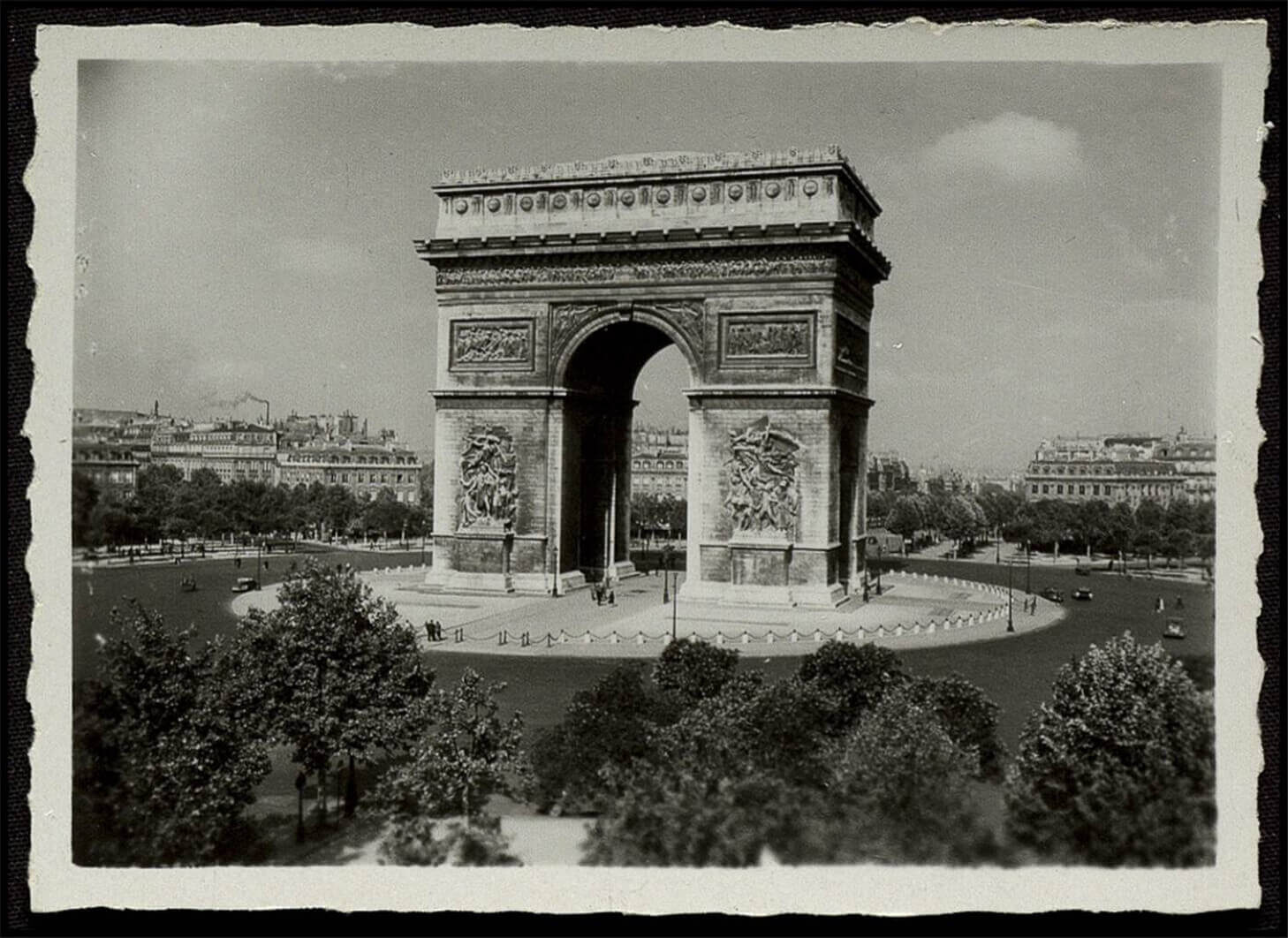 Black and white photo of the Arc de Triomphe in Paris surrounded by trees