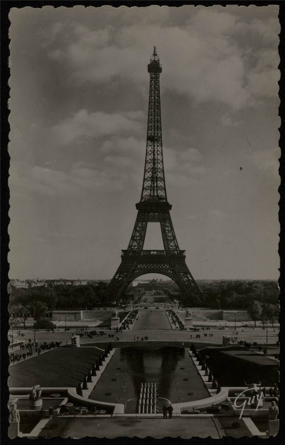 Black and white photo of the Eiffel Tower, with a cloudy sky and trees in the background