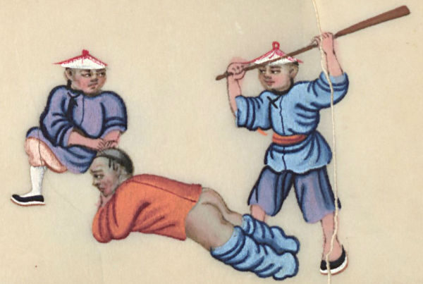 Two boys in traditional clothing playfully interact with a man lying on the ground with his buttocks exposed.