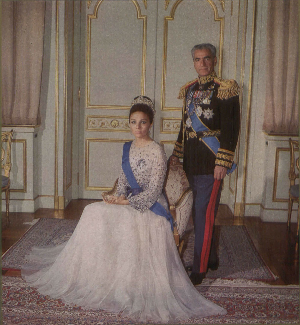 A woman in an elegant gown with a blue sash seated beside a man in a military uniform with decorative elements.
