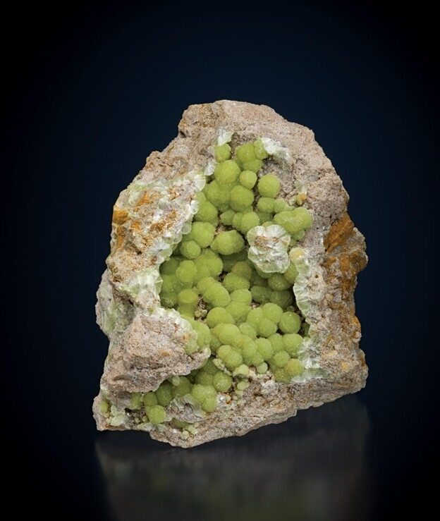 A rough rock with a hollow center filled with green spherical mineral clusters.