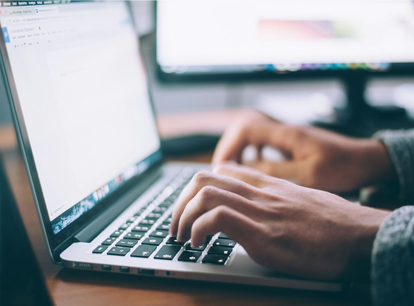 Person typing on a laptop at a desk.