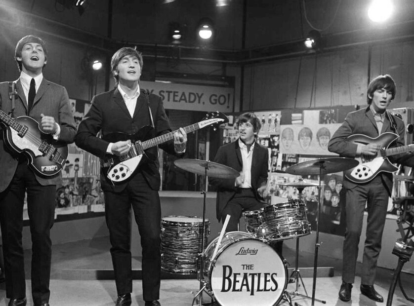 Four band members performing on stage with instruments.