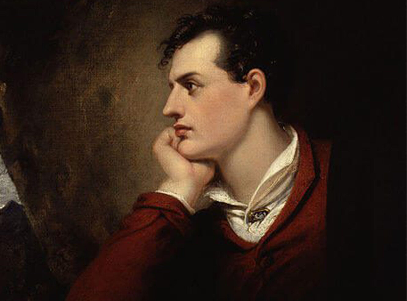 A young man in profile, resting his chin on his hand, thoughtful expression, wearing a red garment