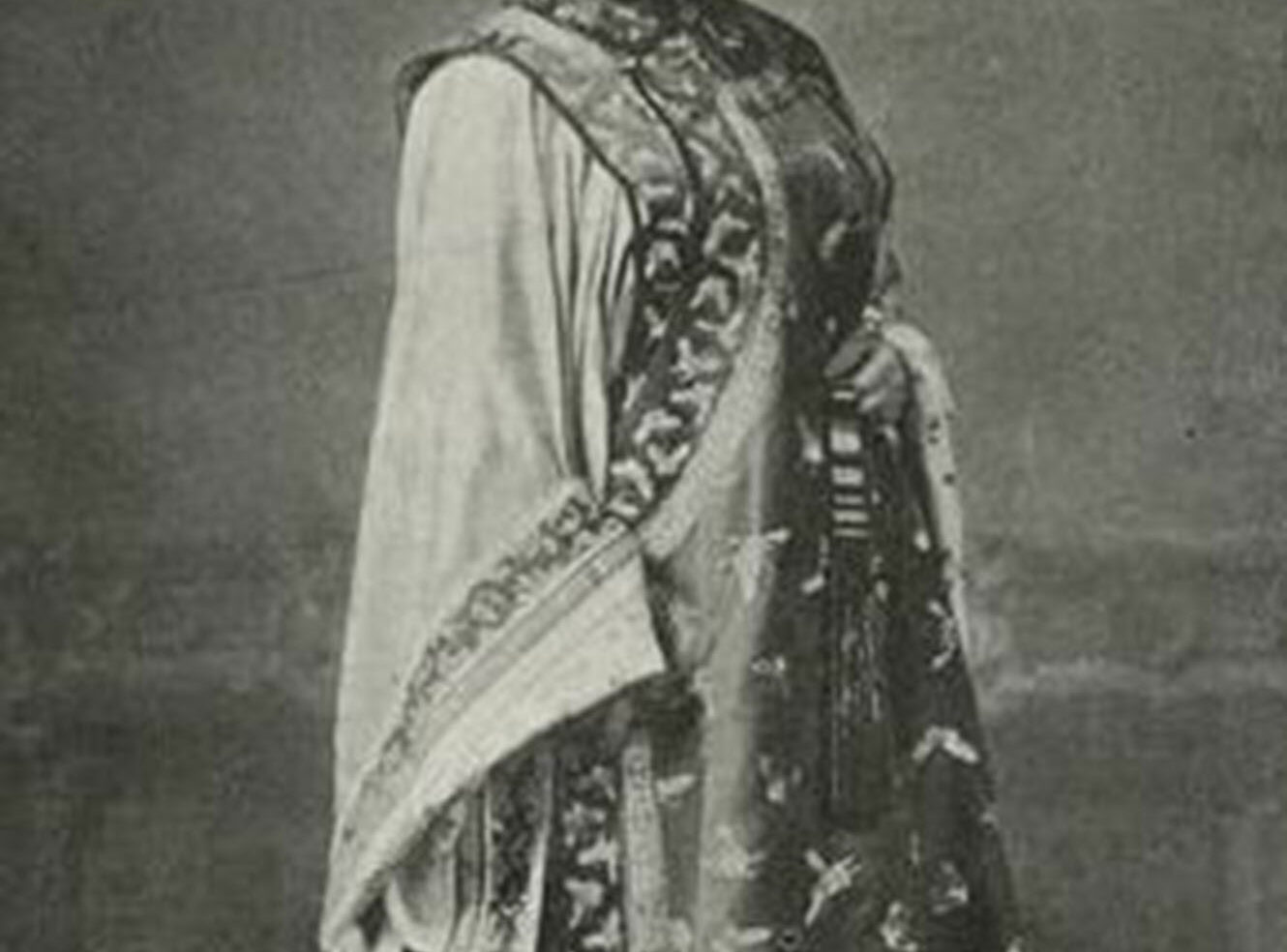 A woman wearing a decorative long dress with intricate patterns and a shawl