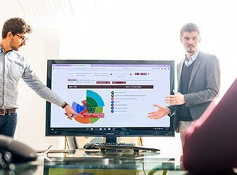 Two people presenting with a large screen in the middle.