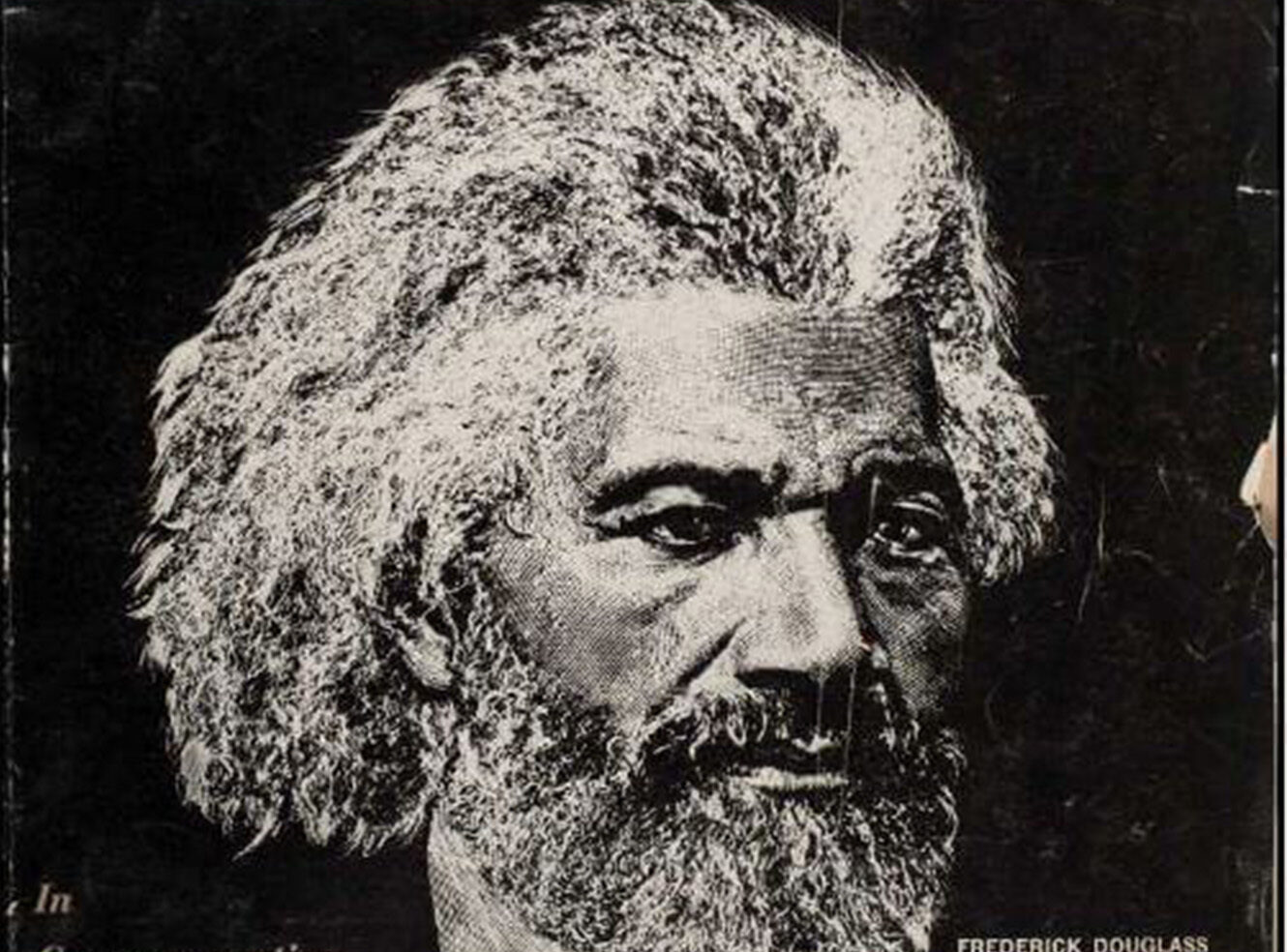A close-up portrait of a man with grey curly hair and a beard, looking serious