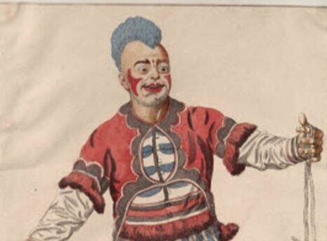 A clown with blue hair and a colourful costume, holding a rope and a paper, smiling.