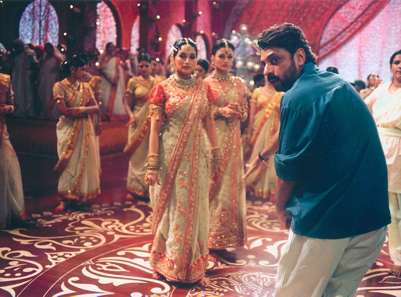 A director gives instructions to dancers in traditional attire.