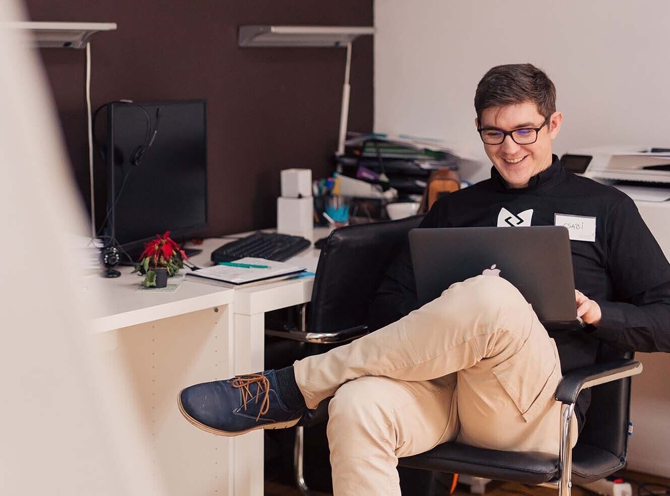 A young student sitting at a laptop, smiling