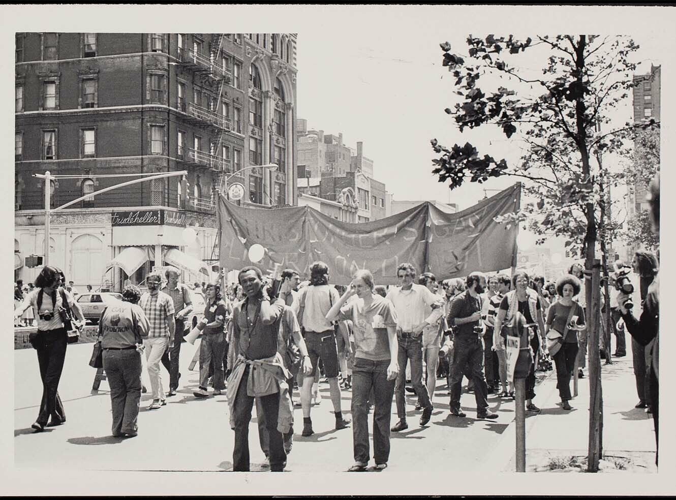 A black and white photo of a crowd holding a large banner during a protest in the city