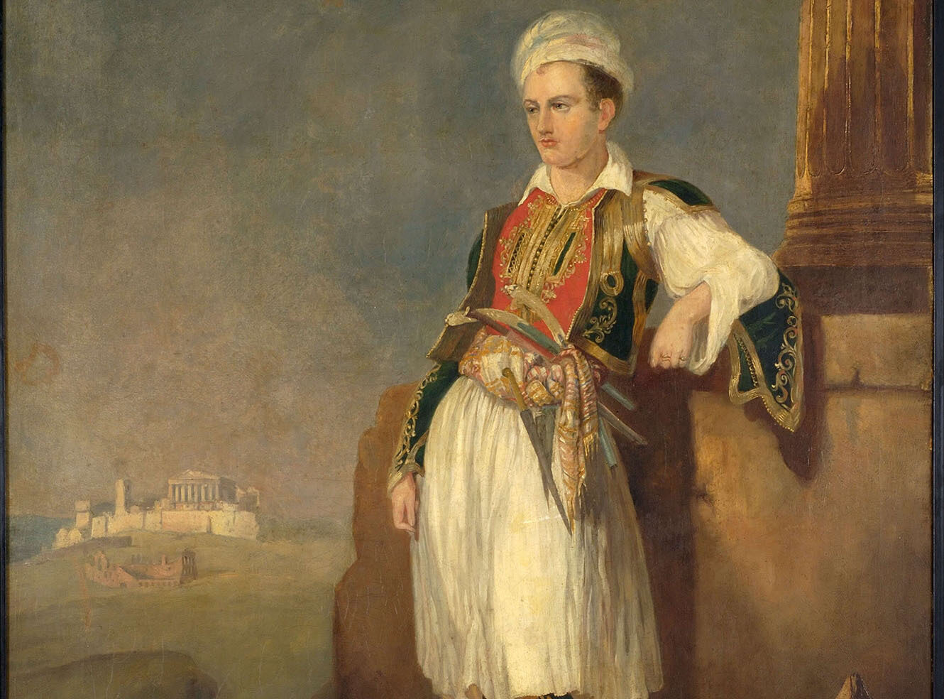 A young man in traditional Greek attire with a feathered hat, standing beside a pillar