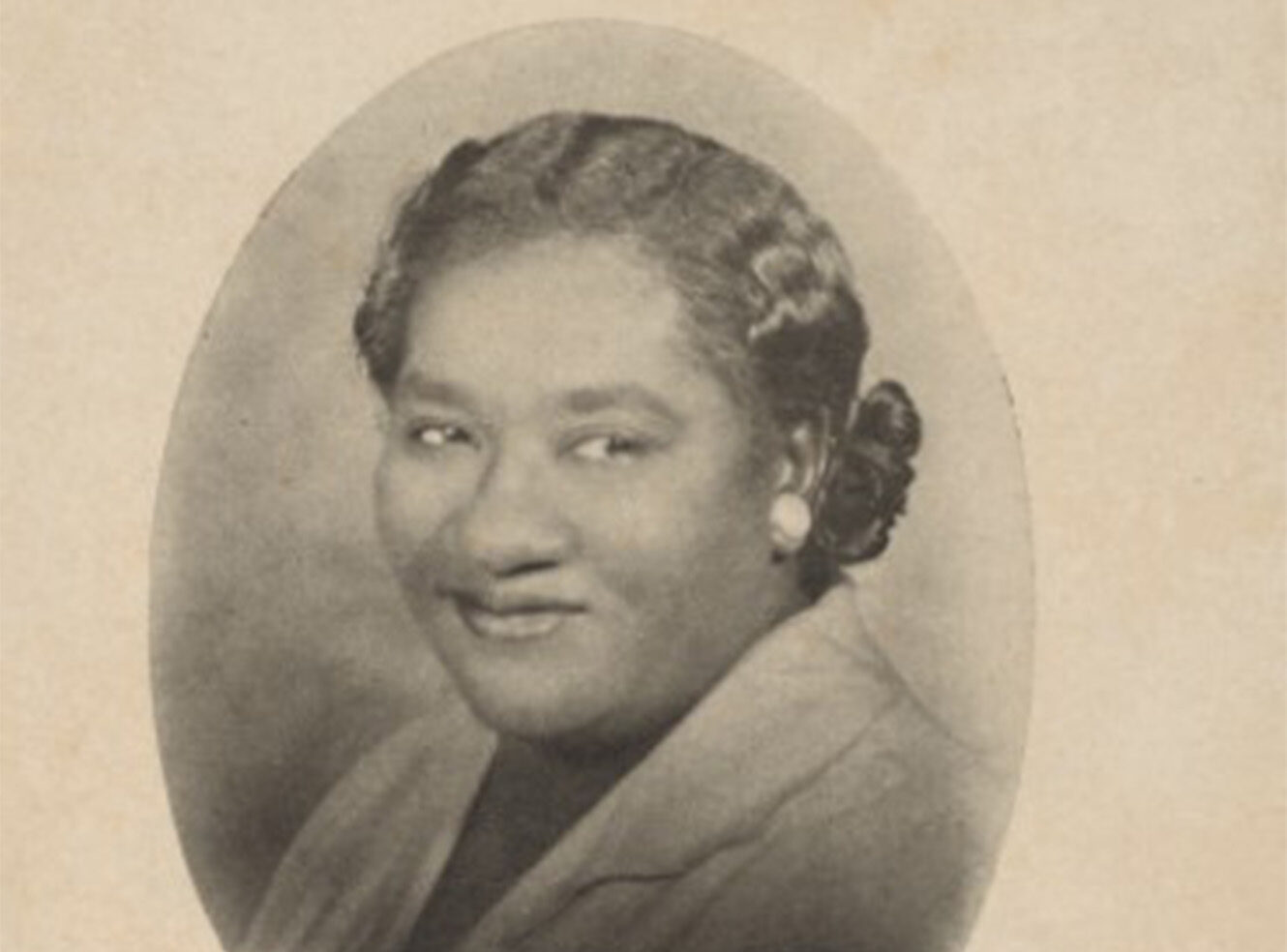 Black and white portrait of a smiling woman with curly hair and earrings