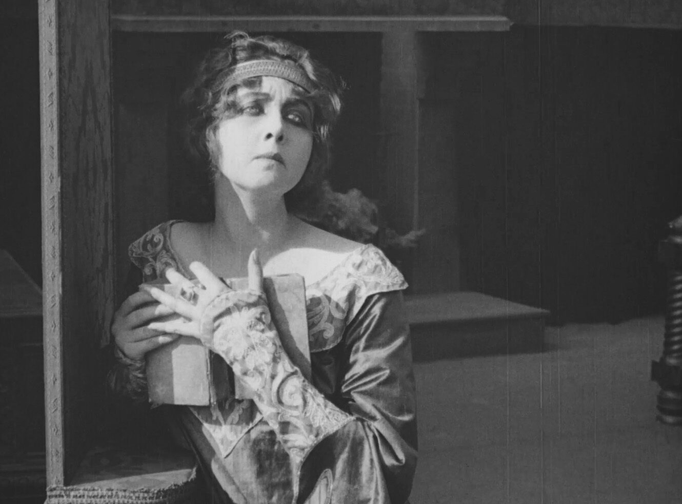 A dramatic black-and-white image portraying a woman in a vintage costume from a silent film.