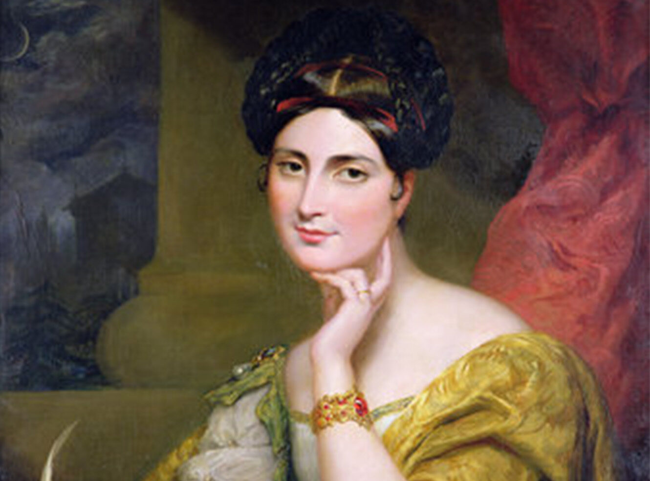 A woman in a yellow dress with elegant jewellery, sitting and resting her chin on her hand