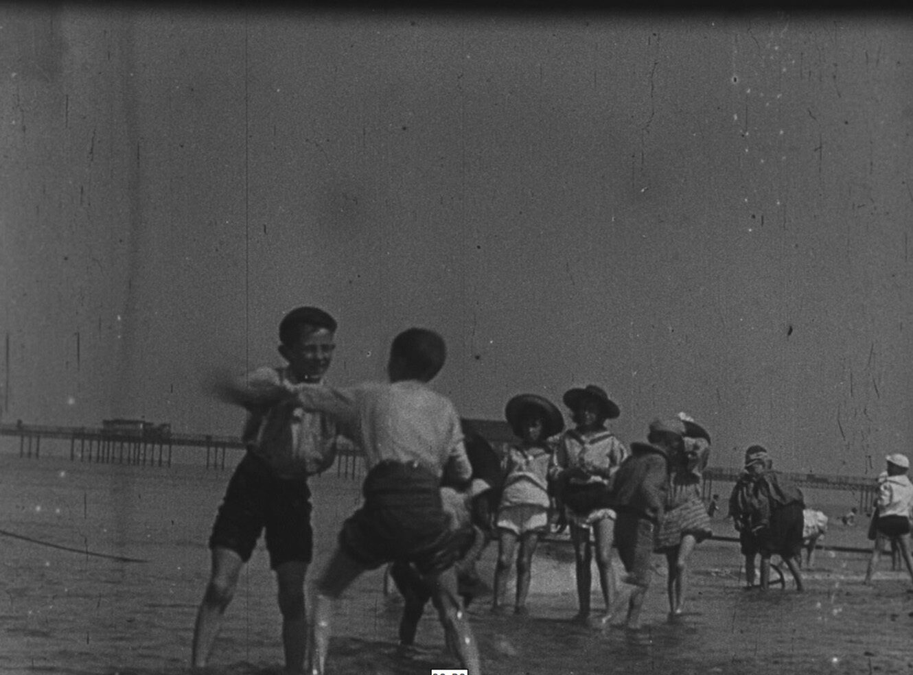 A group of children playing in shallow water at the beach.
