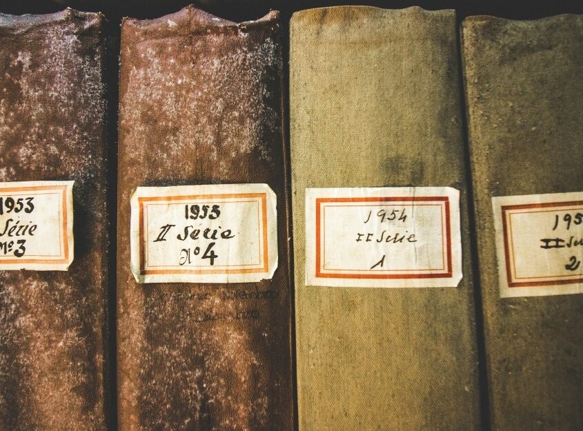 Four old books with worn covers, labeled by year and series numbers from 1953 and 1954.