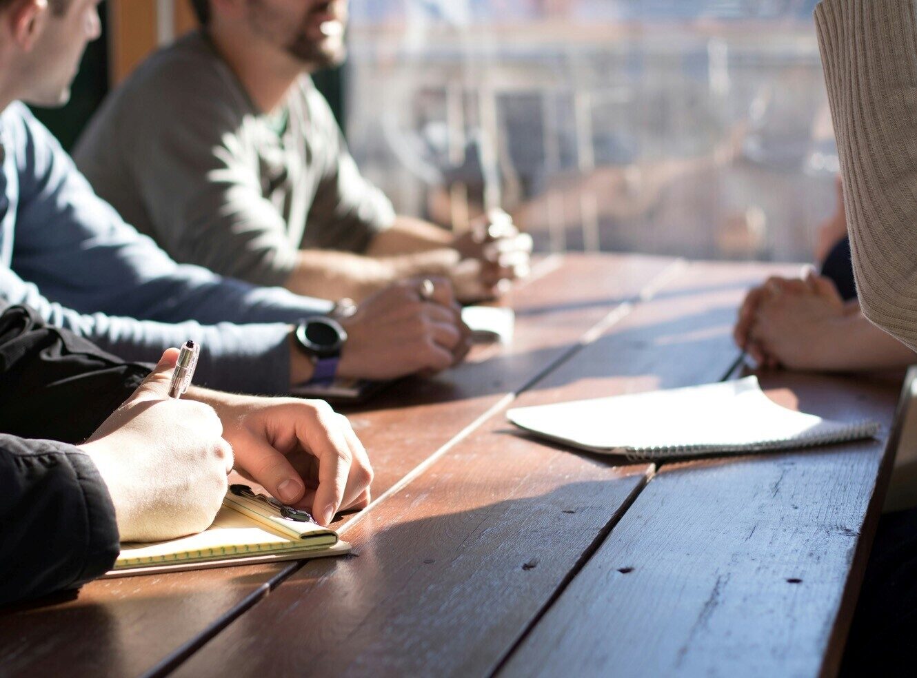 Group of people sitting at a table, taking notes during a meeting.