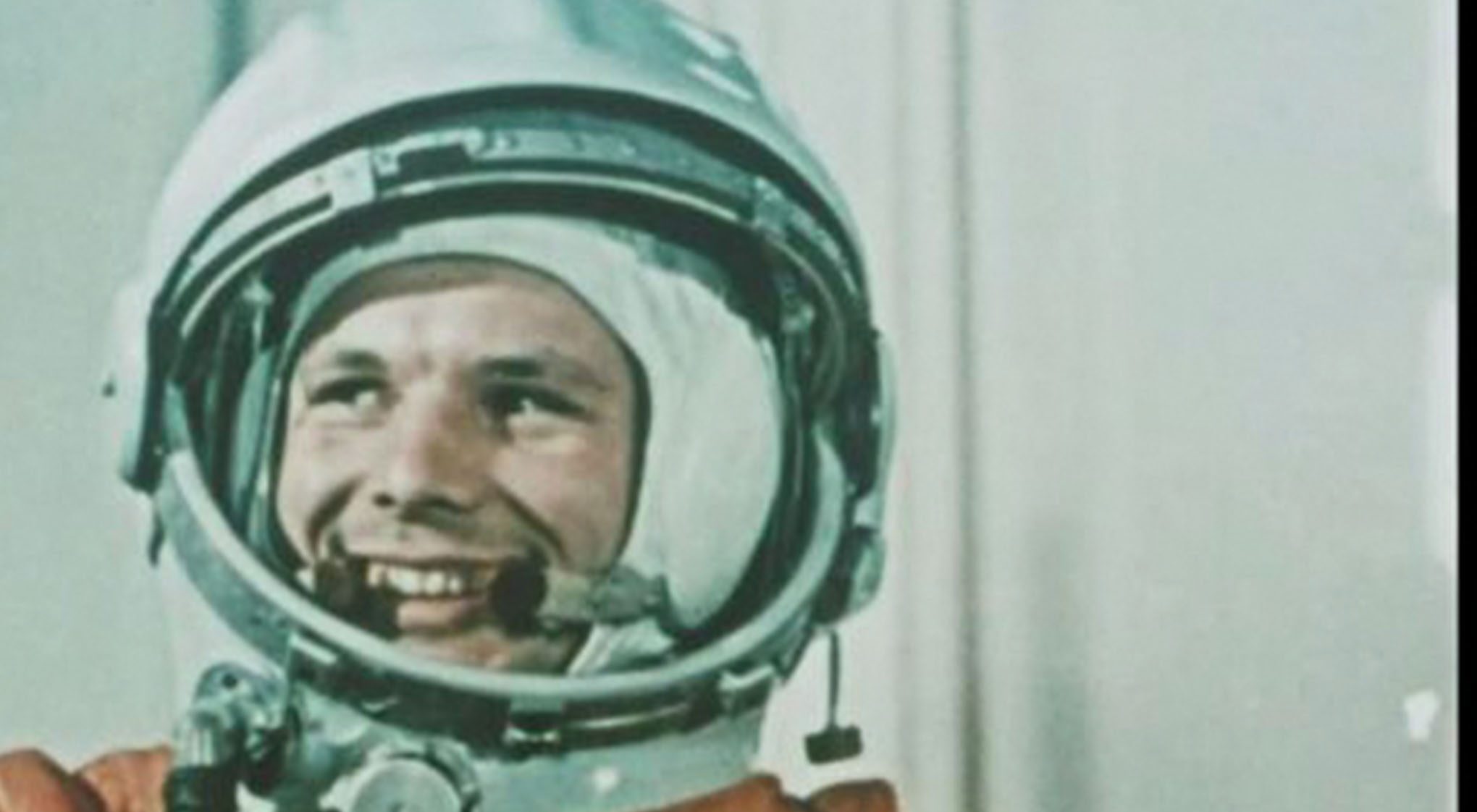 A smiling astronaut in a bright orange suit and helmet, ready for a space mission.