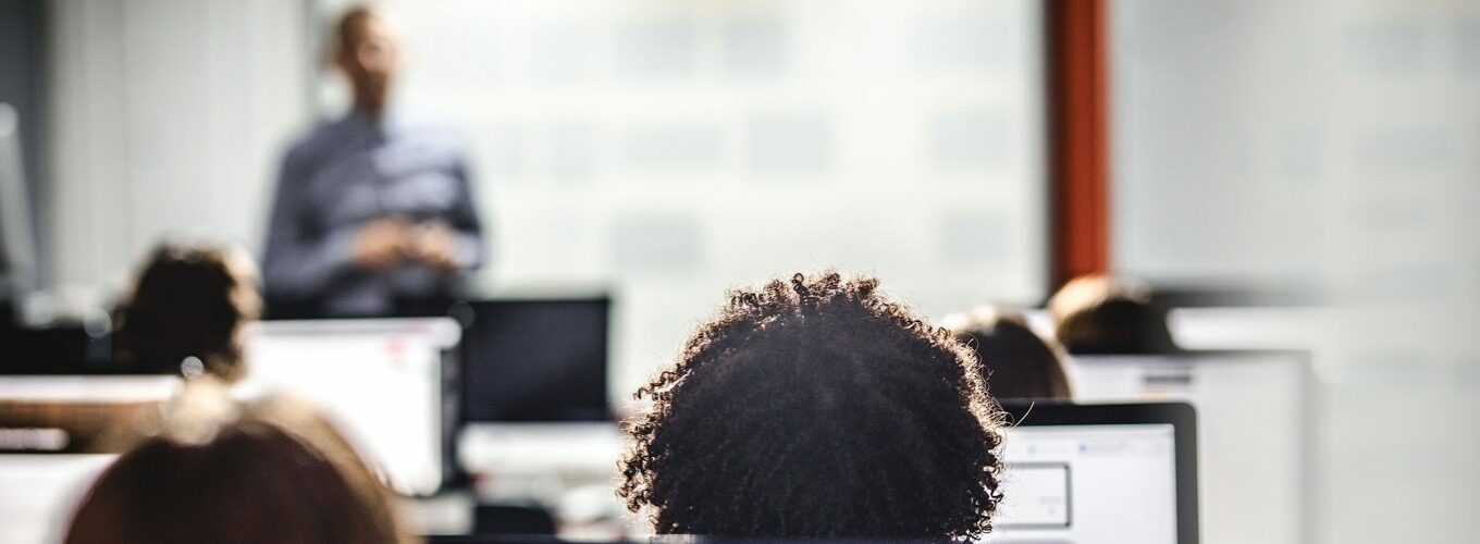 People in a classroom, facing a speaker at the front of the room.