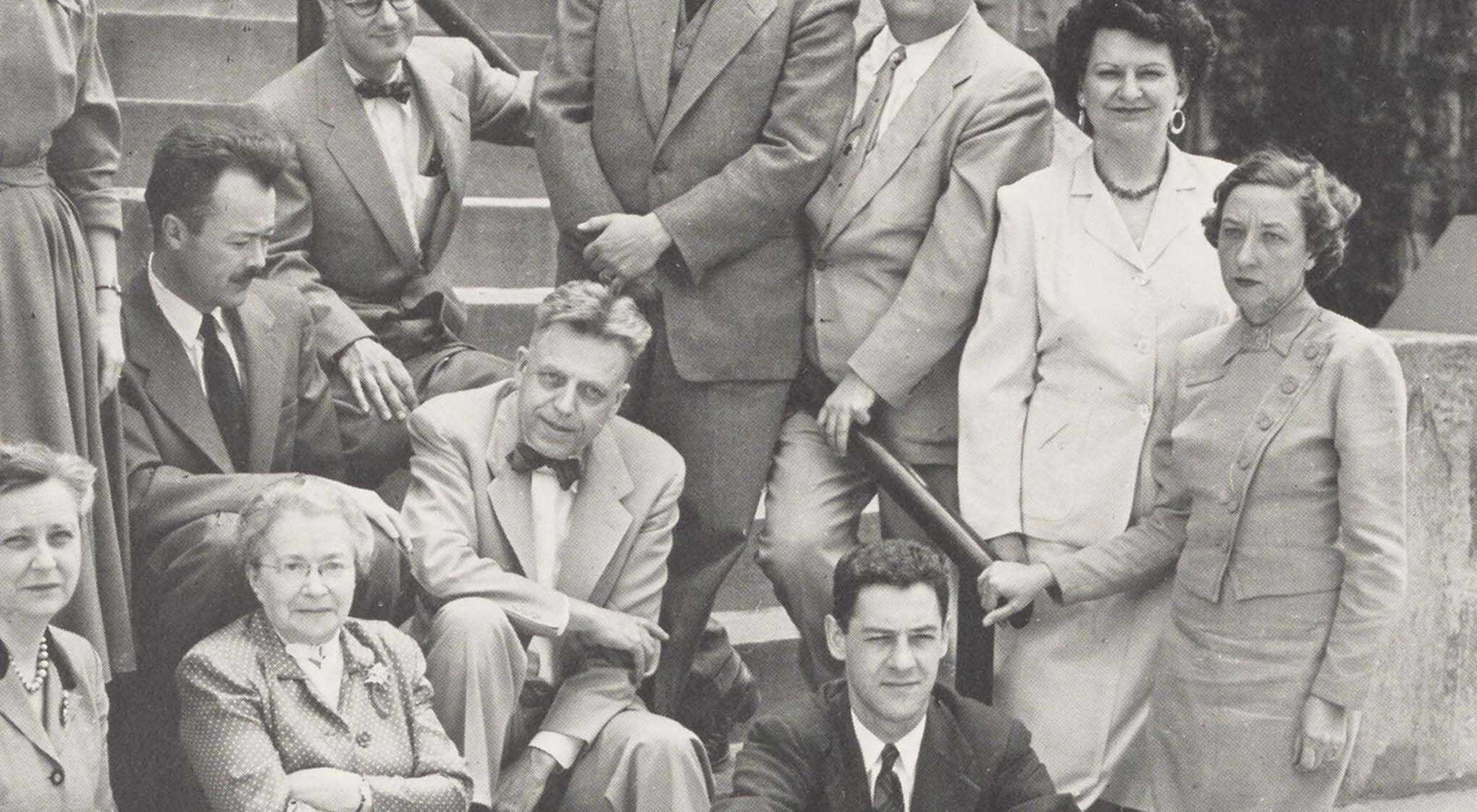 A group photo of eleven people, dressed in 1940s style clothing, posing on outdoor stairs.